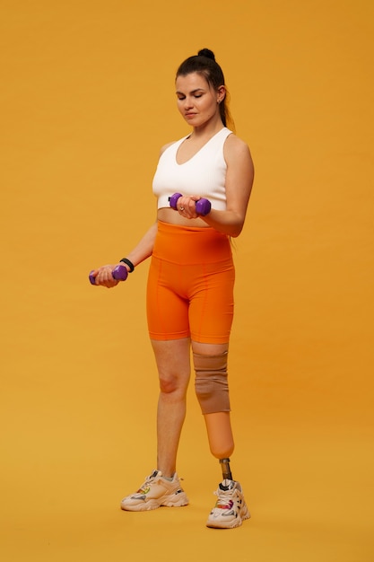 Free photo portrait of disabled woman with prosthetic leg exercising with weights