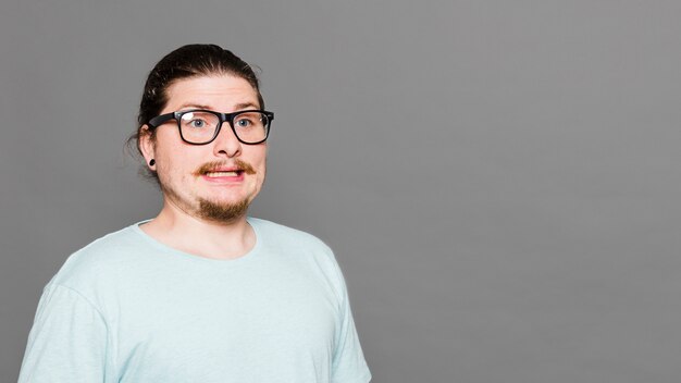 Portrait of a disgusted young man against grey background