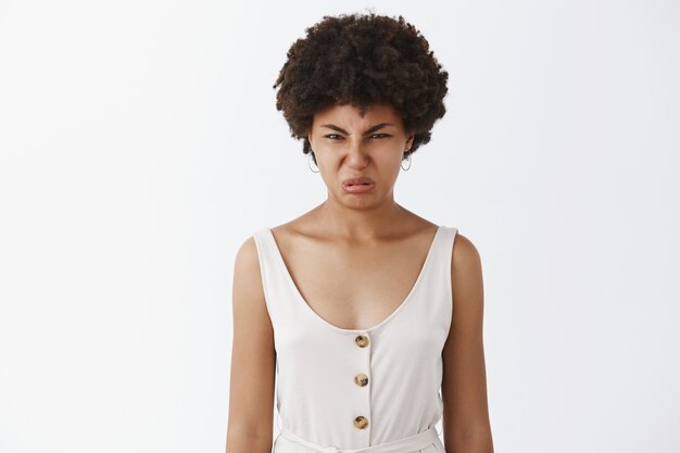 Portrait of displeased African American woman screwing face from dislike and disappointment, wrinkling nose and frowning from awful smell or look, posing