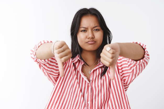 Portrait of displeased and disappointed    woman showing thumbs down