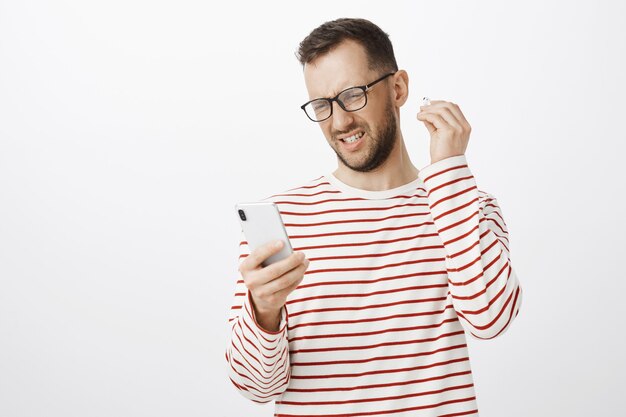 Portrait of displeased frustrated european guy in striped pullover and glasses