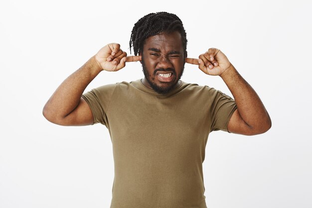 Portrait of displeased guy in a brown t-shirt posing against the white wall