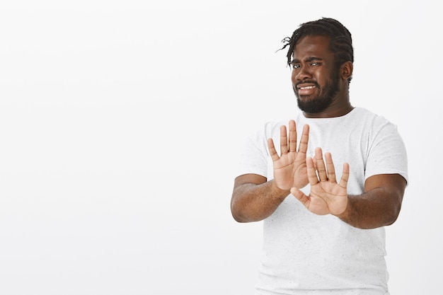 Free photo portrait of displeased guy with braids posing against the white wall