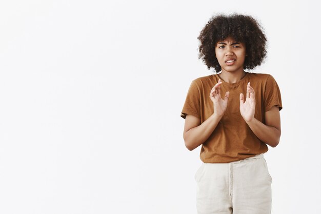 Portrait of displeased intense and unhappy young African American girl with curly hair rejecting offer frowning and lifting upper lip from disgust waving palms near chest