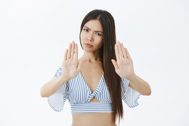 Portrait of displeased serious-looking strict female with long dark hair frowning and pursing lips