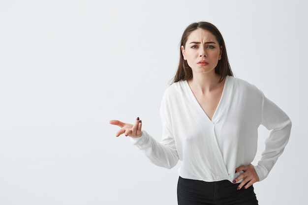 Portrait of displeased young businesswoman with arms akimbo gesturing .