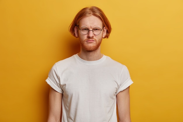 Portrait of dissatisfied bearded ginger man smirks face