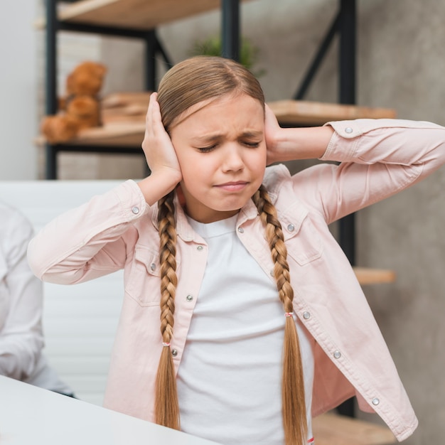 Free photo portrait of a distraught girl covering her ears with two hands