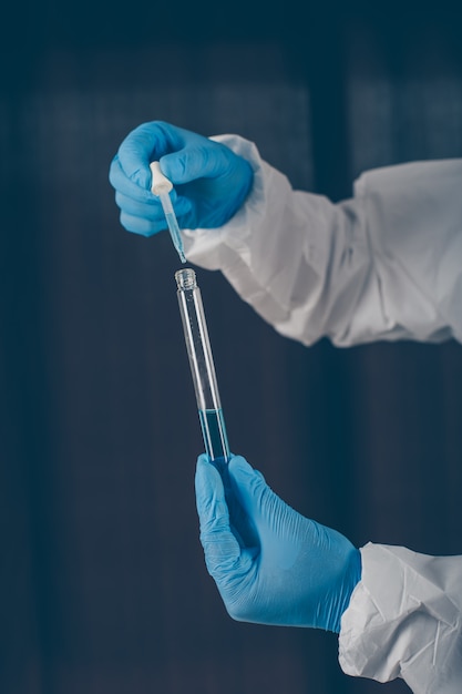 Portrait of a doctor taking medicine samples with mask, gloves and protective suit