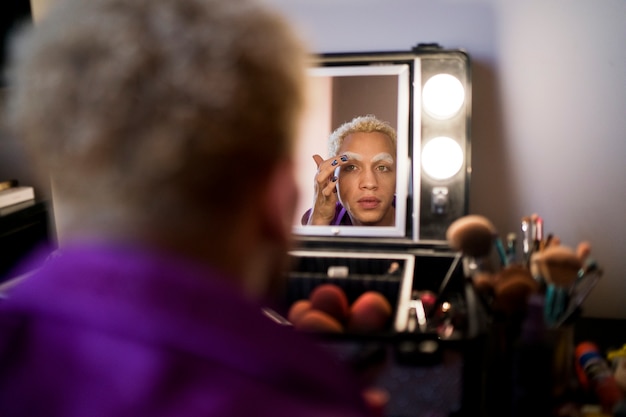 Free photo portrait of drag man putting on makeup