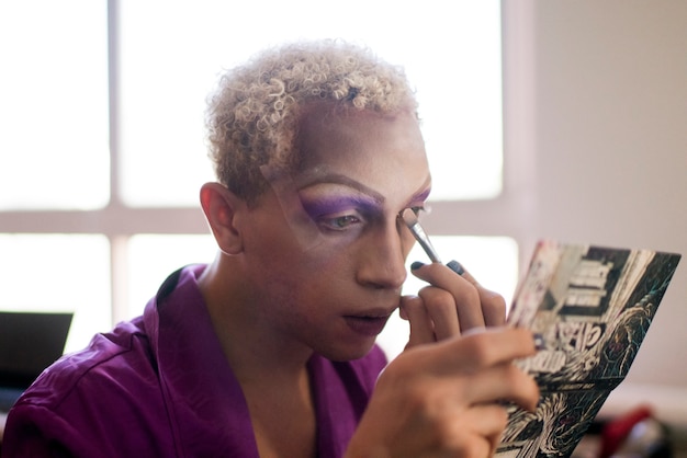 Free photo portrait of drag man putting on makeup