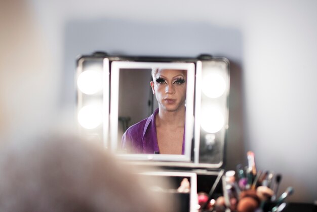 Portrait of drag man putting on makeup