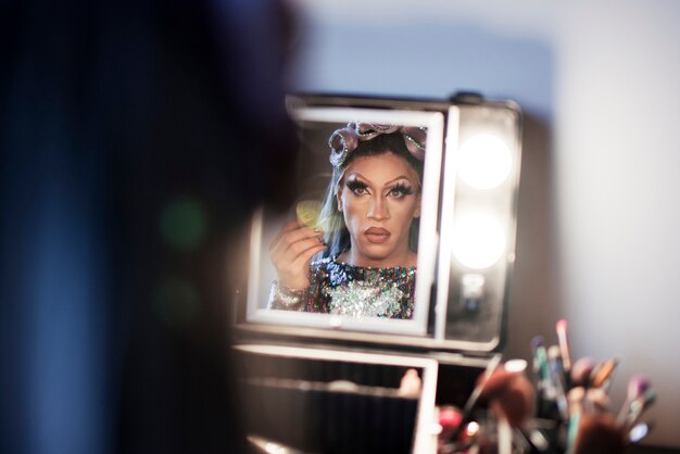 Portrait of drag man putting on makeup