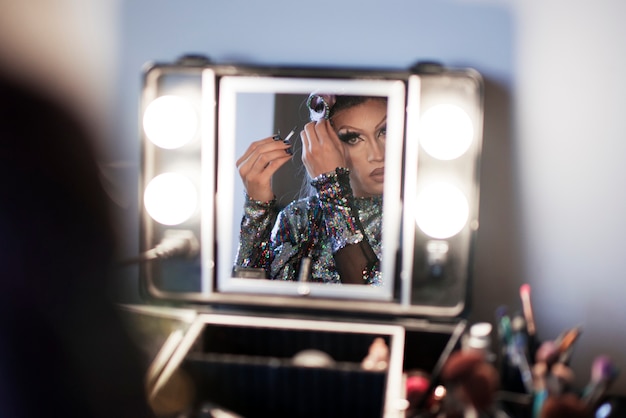 Free photo portrait of drag man putting on makeup