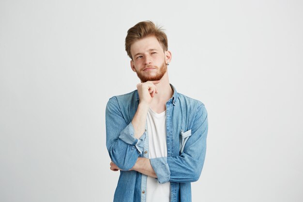 Portrait of dreamy young handsome guy thinking dreaming with hand on chin.