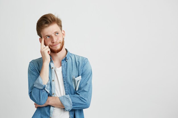 Portrait of dreamy young man thinking looking up with hand on cheek.