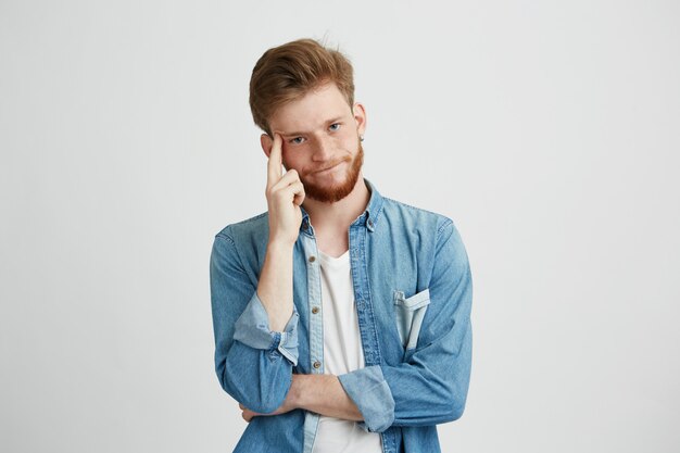 Portrait of dreamy young man thinking with hand on cheek.