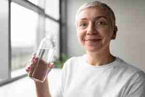 Foto gratuita ritratto di una donna anziana che beve acqua in palestra