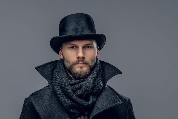 Portrait of an elegant man dressed in a gray jacket and a cylinder hat isolated on grey background.