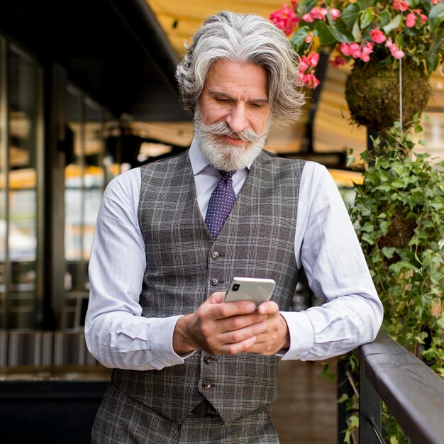 Portrait of elegant mature male holding phone