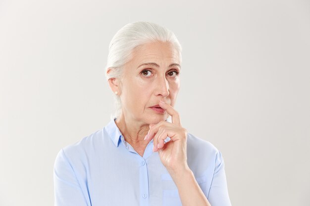 Portrait of elegant mature woman with finger on her lips