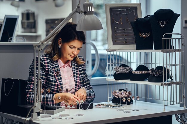 Portrait of elegantly dressed woman seller packs precious earrings in a box for her client in a luxury jewelry store.