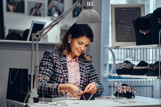 Portrait of elegantly dressed woman seller packs precious earrings in a box for her client in a luxury jewelry store.