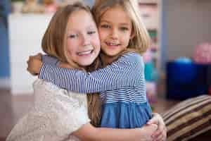 Free photo portrait of embracing sisters in the living room