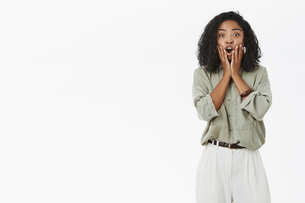 Portrait of emotive impressed dark-skinned female employee reacting on surprising news