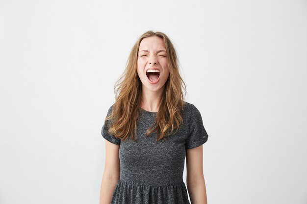 Portrait of emotive young beautiful girl shouting with closed eyes .