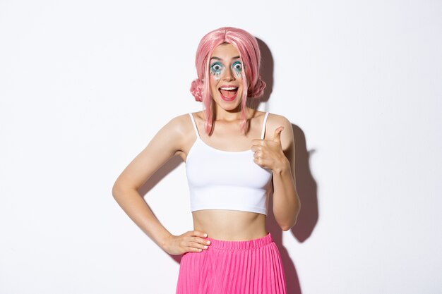 Portrait of enthusiastic attractive female model with pink hair and party makeup