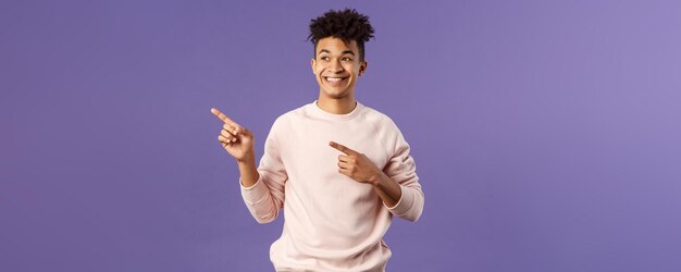 Portrait of enthusiastic goodlooking hispanic man with dreads looking and pointing upper left corner