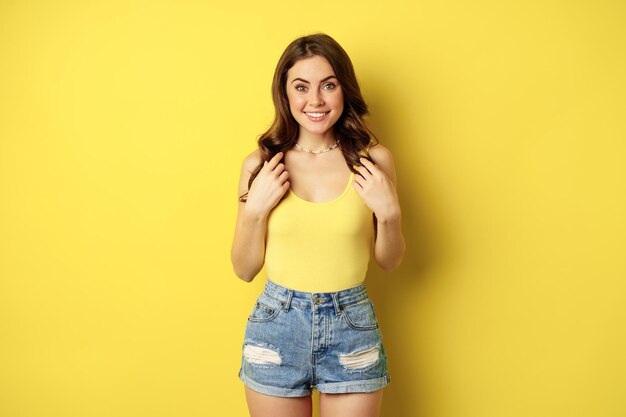 Portrait of enthusiastic, hopeful woman looking with yearning, smiling happy face, expecting smth, desire, standing over yellow background