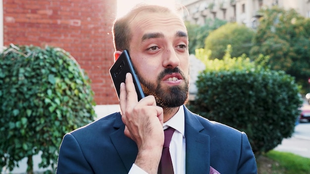 Portrait of entrepreneur talking at phone discussing financial strategy with remote manager explaining company project working at business presentation in front of startup office. outside concept