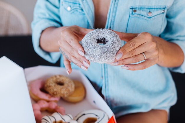 Portrait of european woman with blonde hair enjoying donuts in kitchen at home villa.