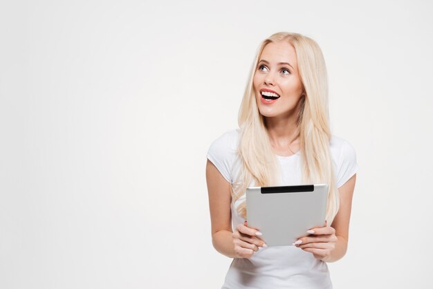 Portrait of an excited blonde woman holding tablet computer