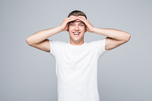 Portrait of an excited boy man holding arms on his head isolated on white