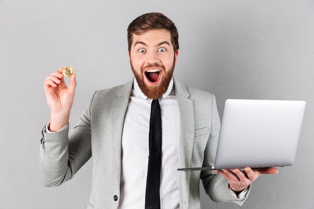 Portrait of an excited businessman showing bitcoin