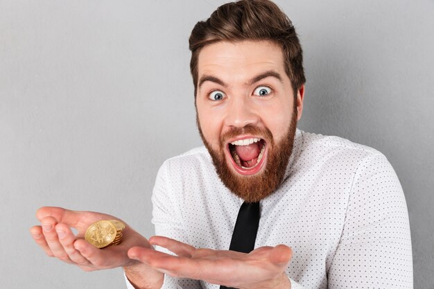 Portrait of an excited businessman showing golden bitcoins