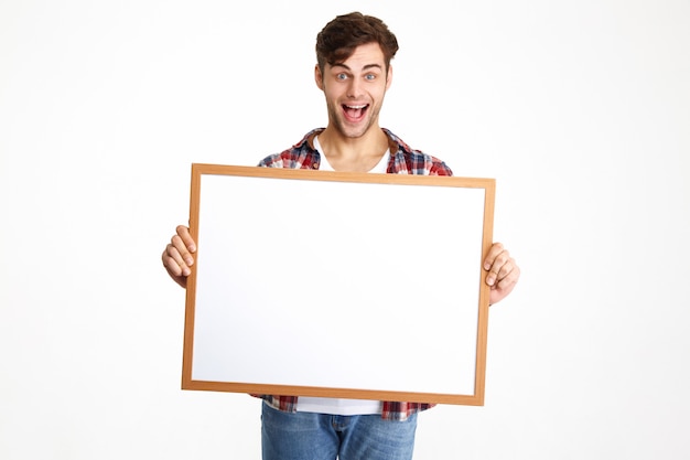 Portrait of an excited cheerful guy holding blank board