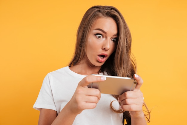 Portrait of an excited cute girl playing games on phone