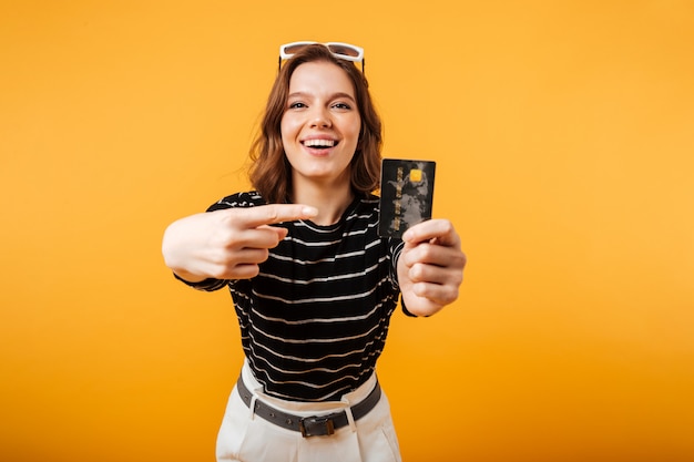 Portrait of an excited girl pointing finger at credit card