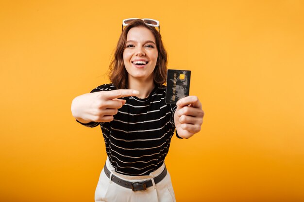 Portrait of an excited girl pointing finger at credit card