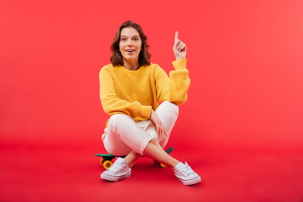 Portrait of an excited girl sitting on a skateboard