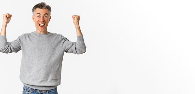 Portrait of excited and happy middleaged man celebrating victory or success raising hands up and say