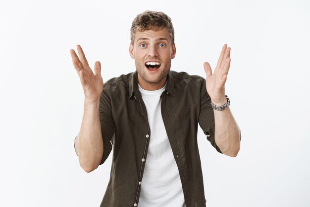 Portrait of excited happy and thrilled impressed handsome european fair-haired male with bristle shaking hands gesturing, shaping something as describing and talking