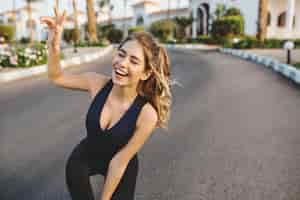 Free photo portrait excited joyful happy sportwoman on strret in tropical city. sunny morning, cheerful mood, expressing true positive emotions, motivation, workout, healthy lifestyle, fitness, attractive model