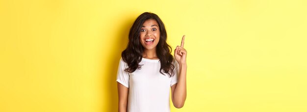 Foto gratuita ritratto di donna afroamericana sorridente eccitata che ha un'idea che alza il dito e le dice sug