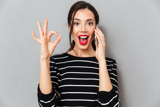 Portrait of an excited woman talking on mobile phone