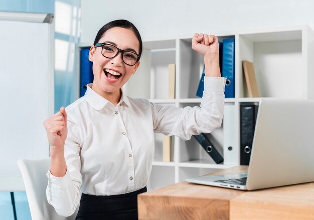 Portrait of a excited young businesswoman cheering at workplace